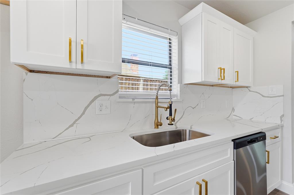 Shaker-style cabinetry with gold hardware, quartz countertops, full-height stone-patterned backsplash, undermount stainless steel sink, and brass-tone gooseneck faucet Shaker-style cabinetry with gold hardware, quartz countertops, full-height stone-patterned backsplash, undermount stainless steel sink, and brass-tone gooseneck faucet
