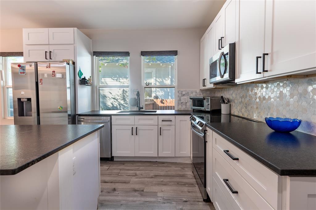 Updated center-island kitchen with an eat-in bar, new cabinetry, stainless-steel appliances, new fixtures, a large farmhouse sink, and lots of natural light.