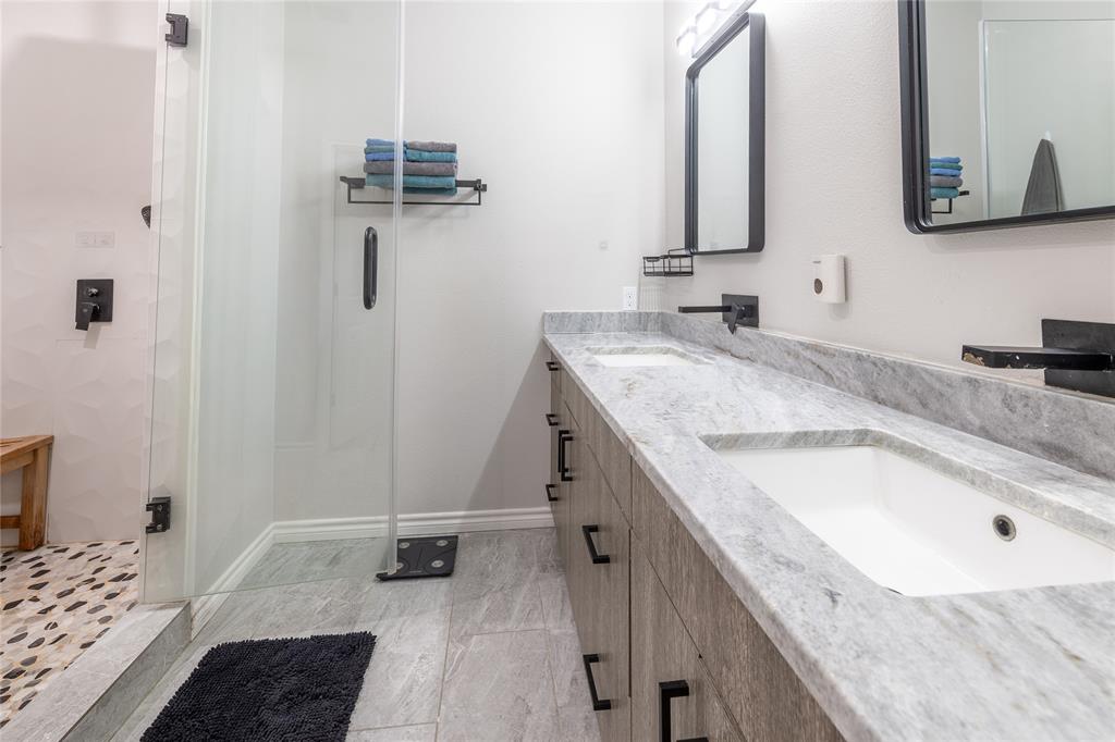 Updated primary bathroom with a walk-in shower, stone countertops, dual undermounted sinks, modern vanity, and modern fixtures.