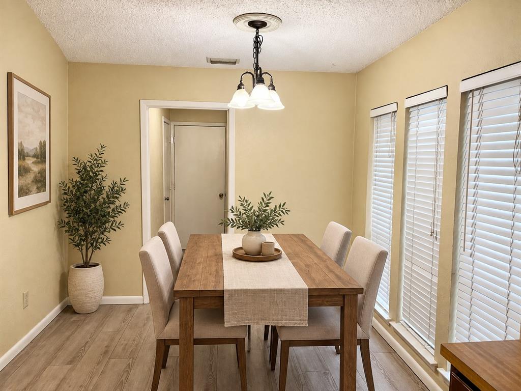 Wood-finish flooring, multi-pane light fixture with a ceiling medallion, and a series of three windows featuring horizontal blinds