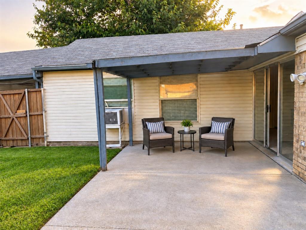 Covered concrete patio featuring a structural pergola, light-colored horizontal siding, and wood-panel fencing