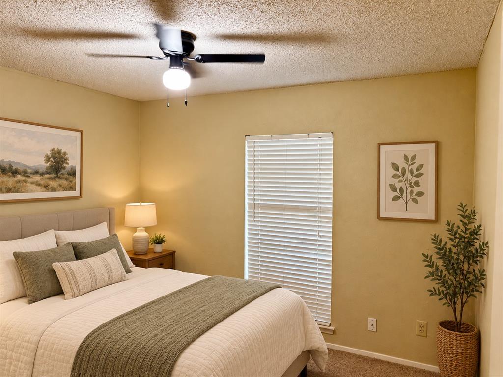 Room featuring neutral wall paint, textured ceiling, carpeted flooring, window with horizontal blinds, and a mounted ceiling fan with integrated light fixture