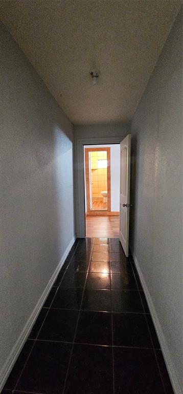 Hallway featuring dark square tile flooring, neutral painted walls, and a single-panel interior door