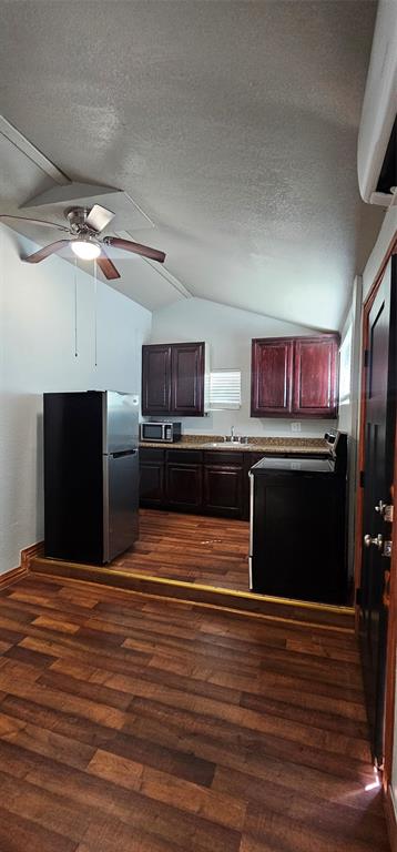 Kitchen featuring dark wood cabinetry, stone-finish countertops, stainless steel refrigerator, wood-finish flooring, and a ceiling fan