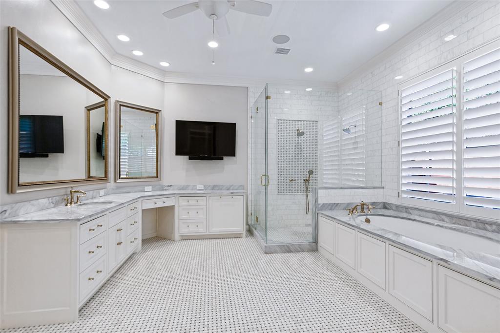 Luxurious Primary Bath provides beautiful marble countertops, soaking tub, and frameless glass shower.  View of "her" vanity.