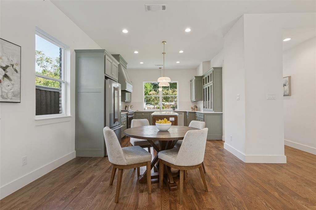Kitchen featuring sage-toned cabinetry, an island with countertop seating, stainless steel appliances, recessed ceiling lighting, and wood-finish flooring