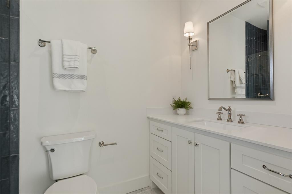 White shaker-style cabinetry vanity with a solid surface countertop, undermount sink, wall-mounted polished nickel faucet, and rectangular framed mirror