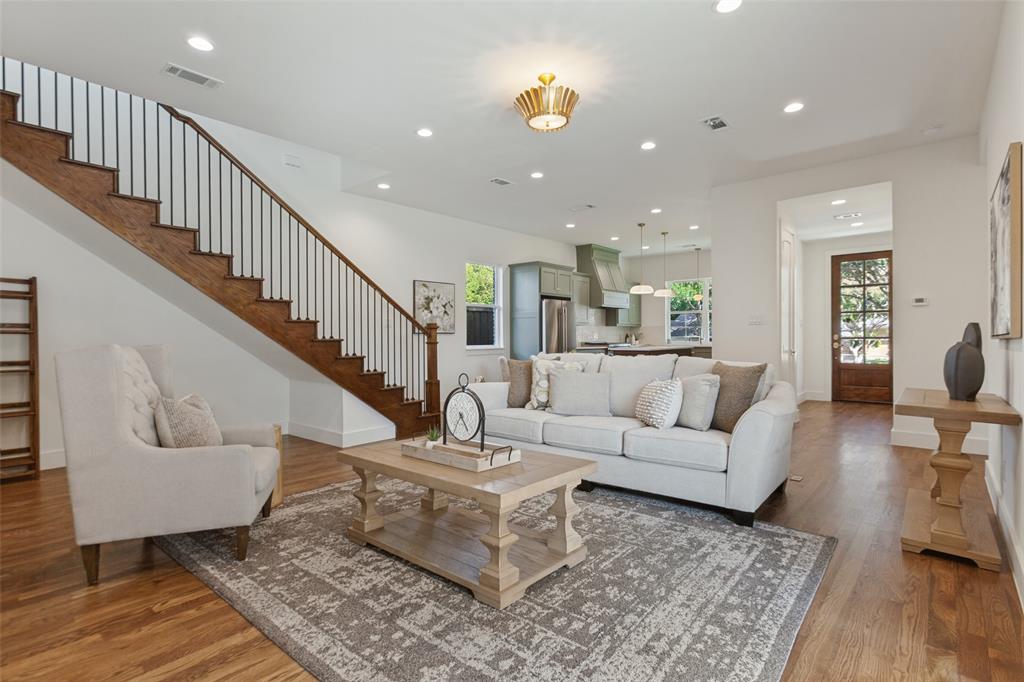 Open-concept living space featuring wood-finish flooring, recessed lighting, and a staircase with a wood handrail and metal balusters