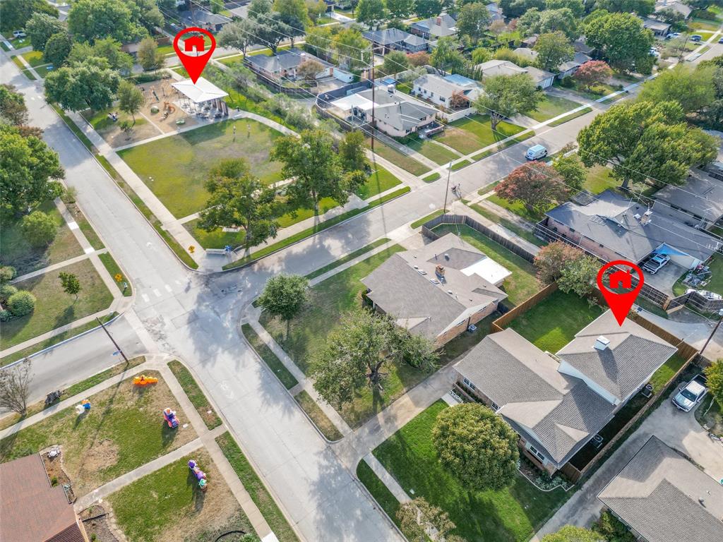 Aerial perspective showcasing a corner lot property featuring a composition shingle roof, chimney, and proximity to public greenspace
