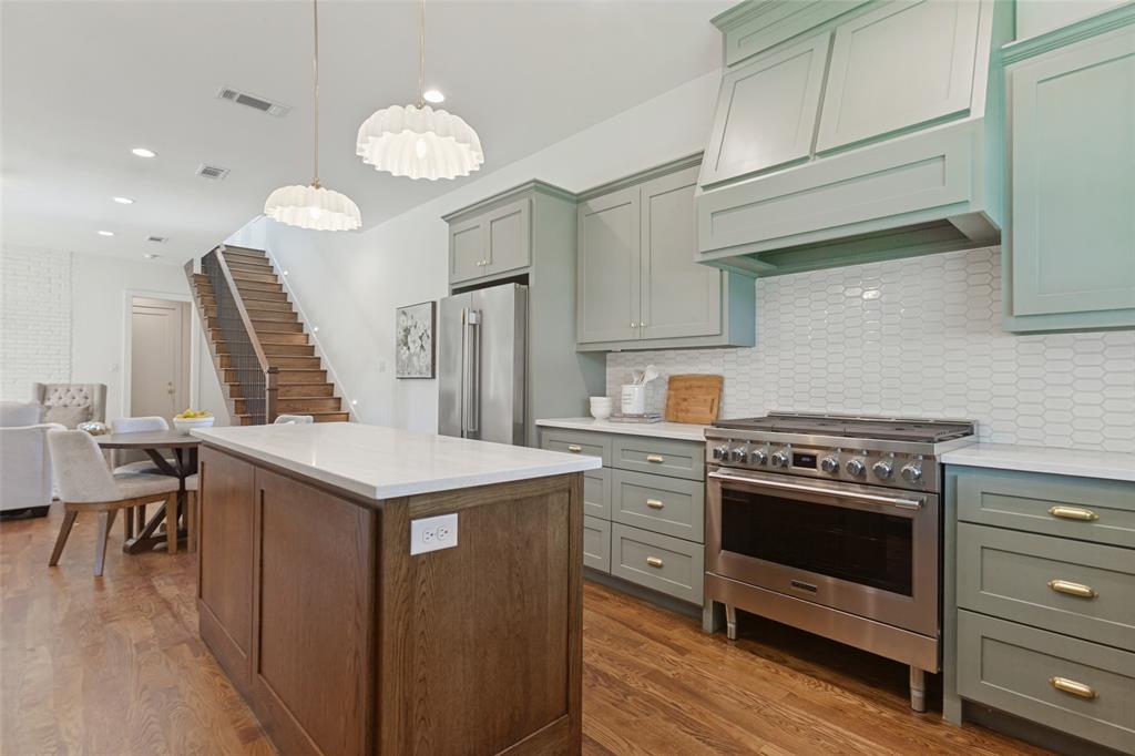 Kitchen featuring sage green cabinetry, a wood-finish island, a stainless steel gas range with a custom hood, and a white picket-style tile backsplash