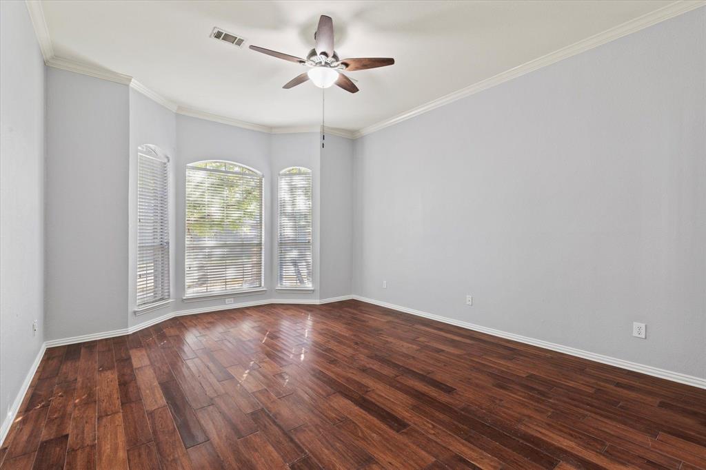 Room featuring dark wood-finish flooring, a multi-window bay configuration with arched top panes, and a central ceiling fan with integrated lighting
