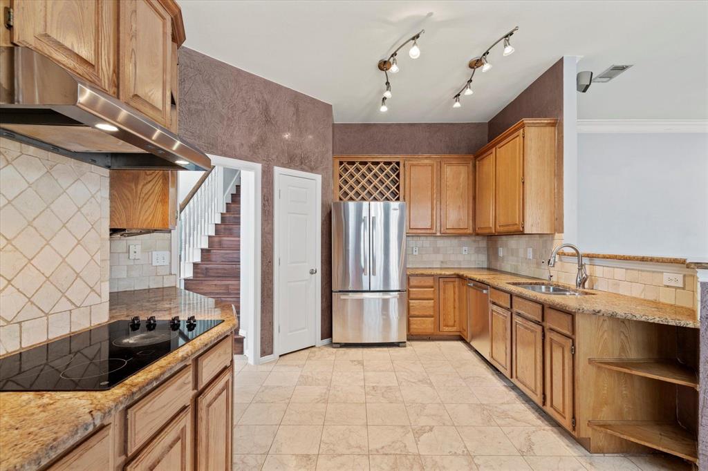 Kitchen featuring stained-wood cabinetry, stone countertops, diamond-pattern tile backsplash, stainless steel appliances, and built-in wine storage