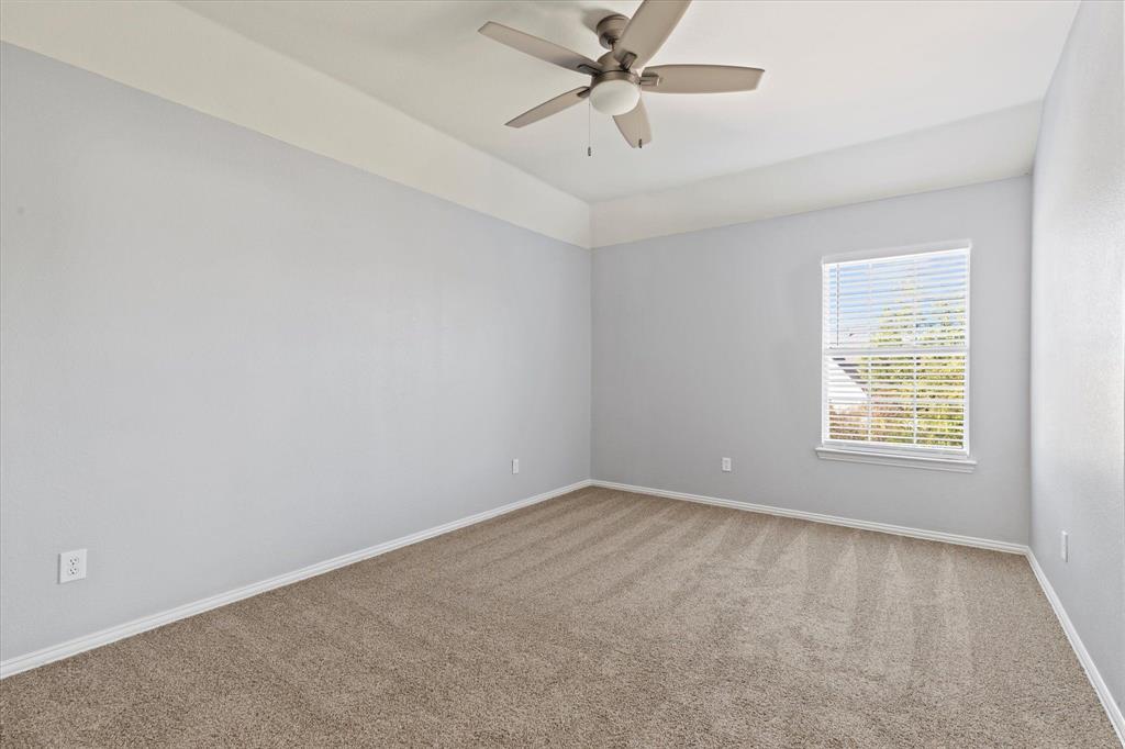 Room featuring neutral carpeting, a tray ceiling, and a five-blade ceiling fan with a central light fixture