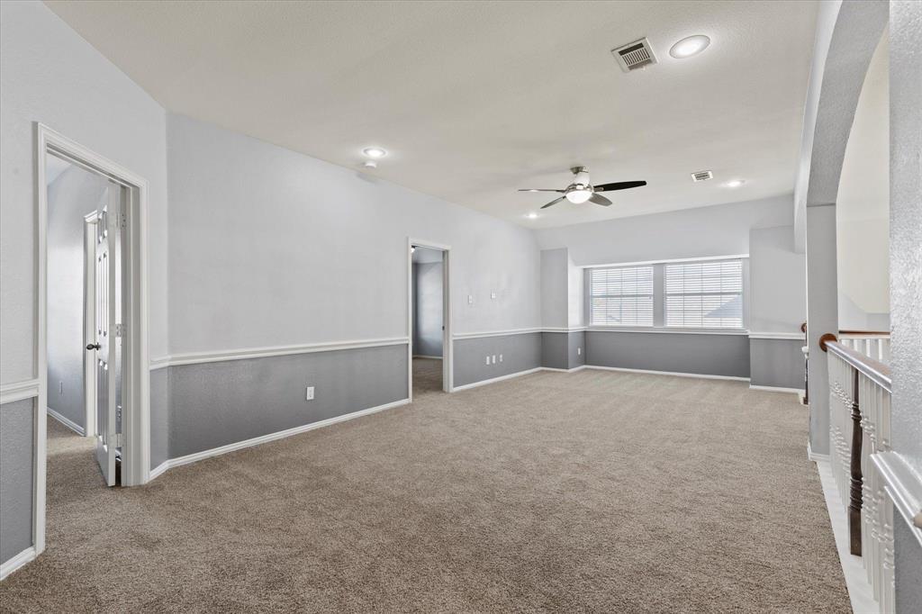 Upstairs Living Area. Spacious room featuring high ceilings, neutral carpeting, two-toned wall paint, recessed lighting, and a ceiling fan