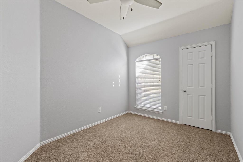 Vaulted ceilings, neutral wall color, arched window with horizontal blinds, neutral carpeting, and a ceiling-mounted fan