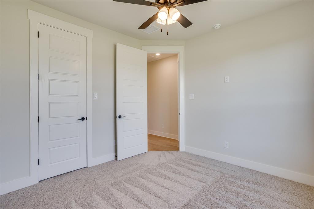 Neutral-toned carpeted flooring, five-panel shaker-style interior doors with matte black hardware, and an overhead ceiling fan with integrated lighting