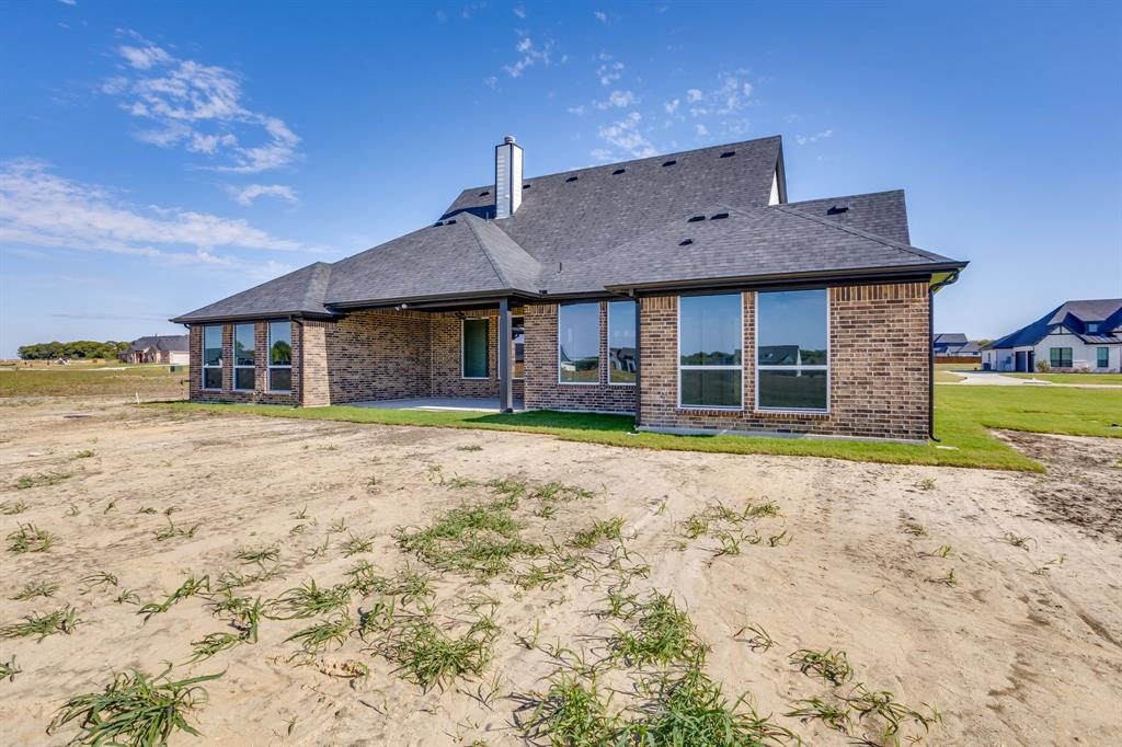 Brick exterior featuring a covered patio, pitched roofline, chimney stack, and multi-pane windows