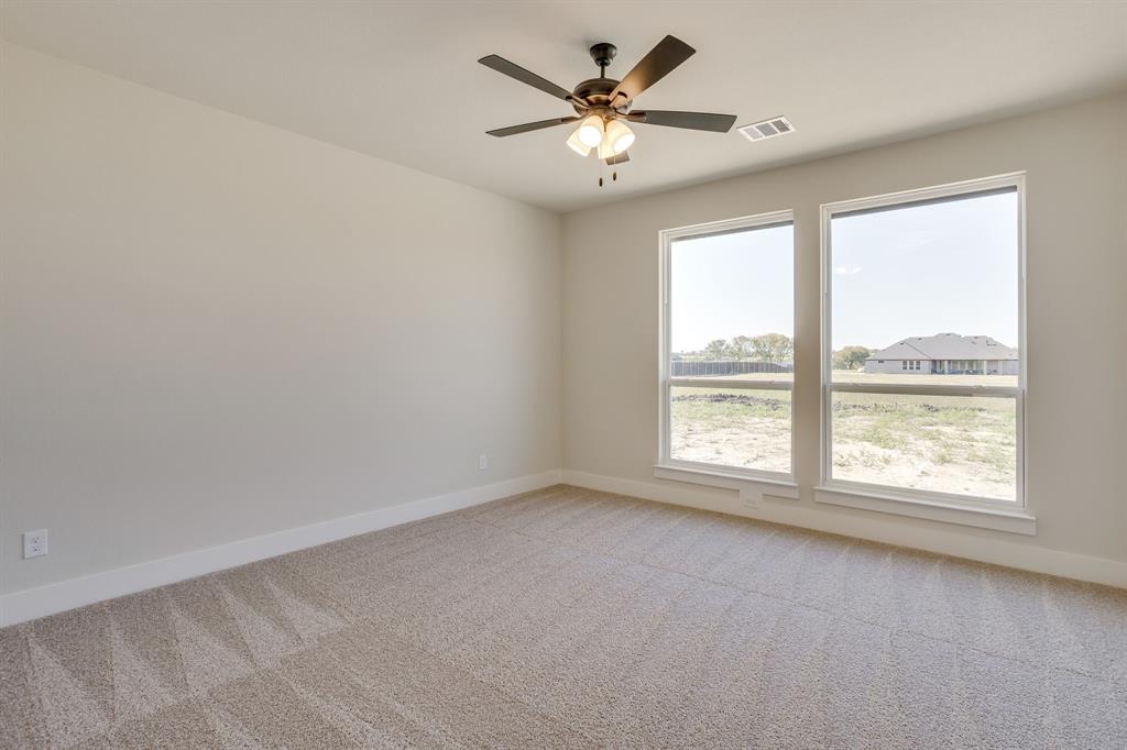 Neutral-toned interior featuring wall-to-wall carpeting, dual windows, and a ceiling-mounted light fixture with a multi-blade fan