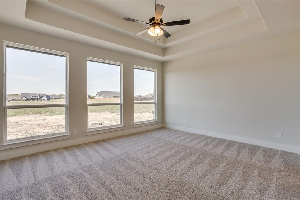Tray ceiling with a central multi-blade ceiling fan and three large picture windows providing natural light