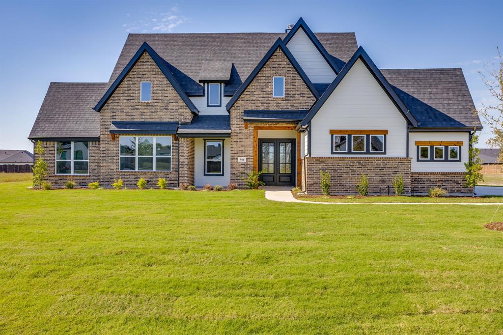 Multi-gabled exterior featuring brick and horizontal siding, a covered entryway with double doors, wood-trimmed windows, and a paved walkway
