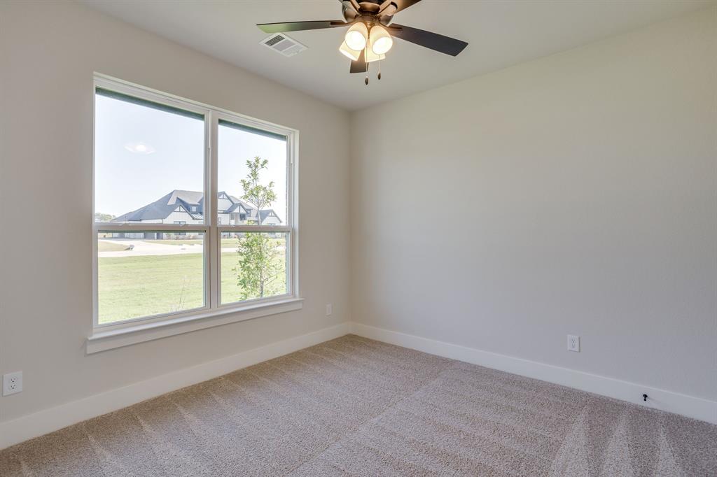 Neutral-toned interior featuring plush carpeting, a large window with exterior exposure, and a ceiling-mounted fan with integrated lighting