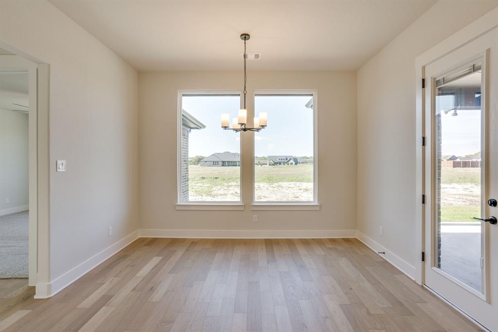 Light-filled room featuring wood-finish flooring, dual picture windows, an overhead multi-light chandelier, and a glass-paneled exterior door
