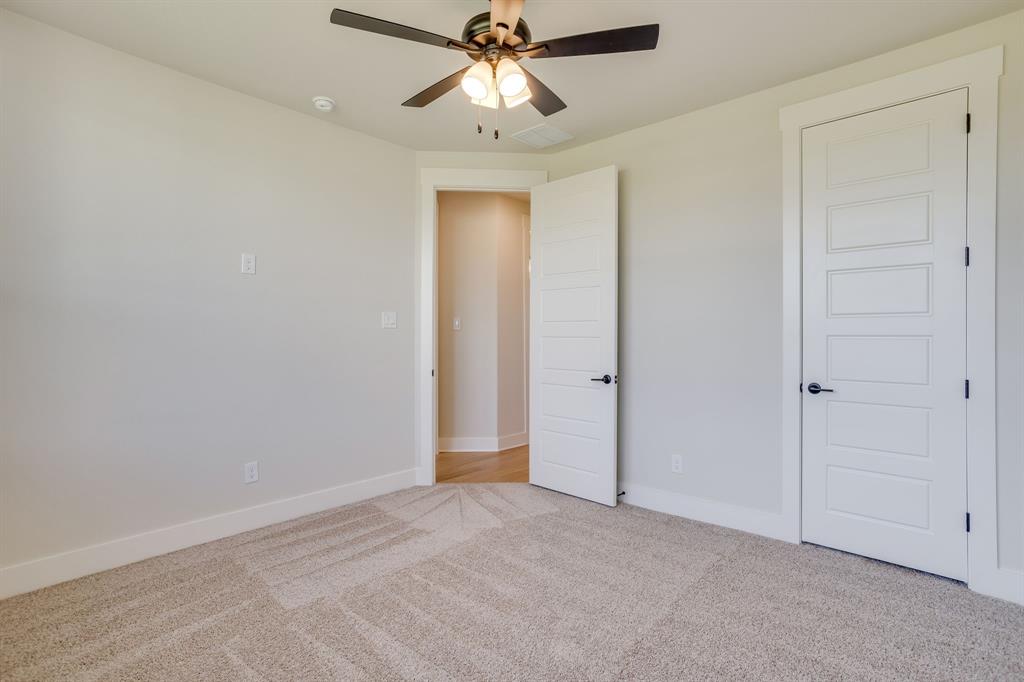 Neutral-toned carpeted room featuring a ceiling fan with integrated lighting and five-panel interior doors with matte black hardware
