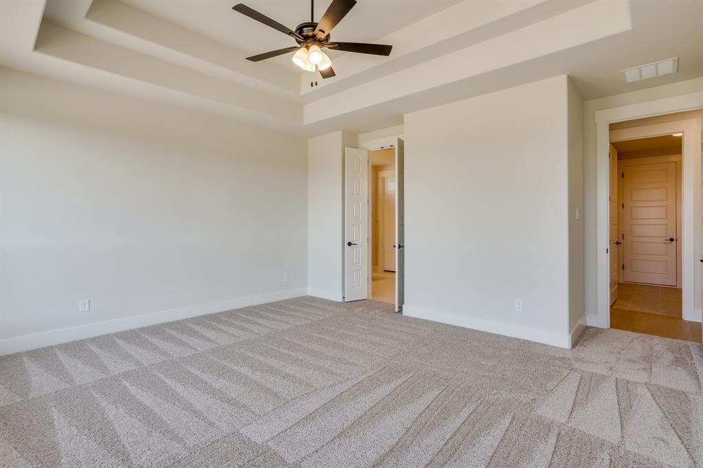 Tray ceiling with a central multi-blade ceiling fan and integrated lighting, neutral wall-to-wall carpeting, and multi-panel interior doors