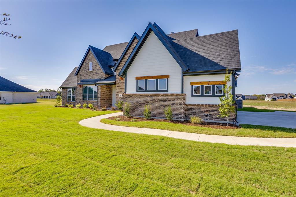 Exterior facade featuring brick masonry and horizontal siding, high-pitched gabled rooflines, dark-framed windows with wood-accent headers, and a concrete walkway