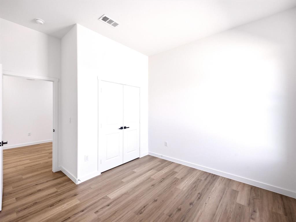 Interior space featuring high ceilings, wood-finish flooring, and double closet doors with matte black hardware