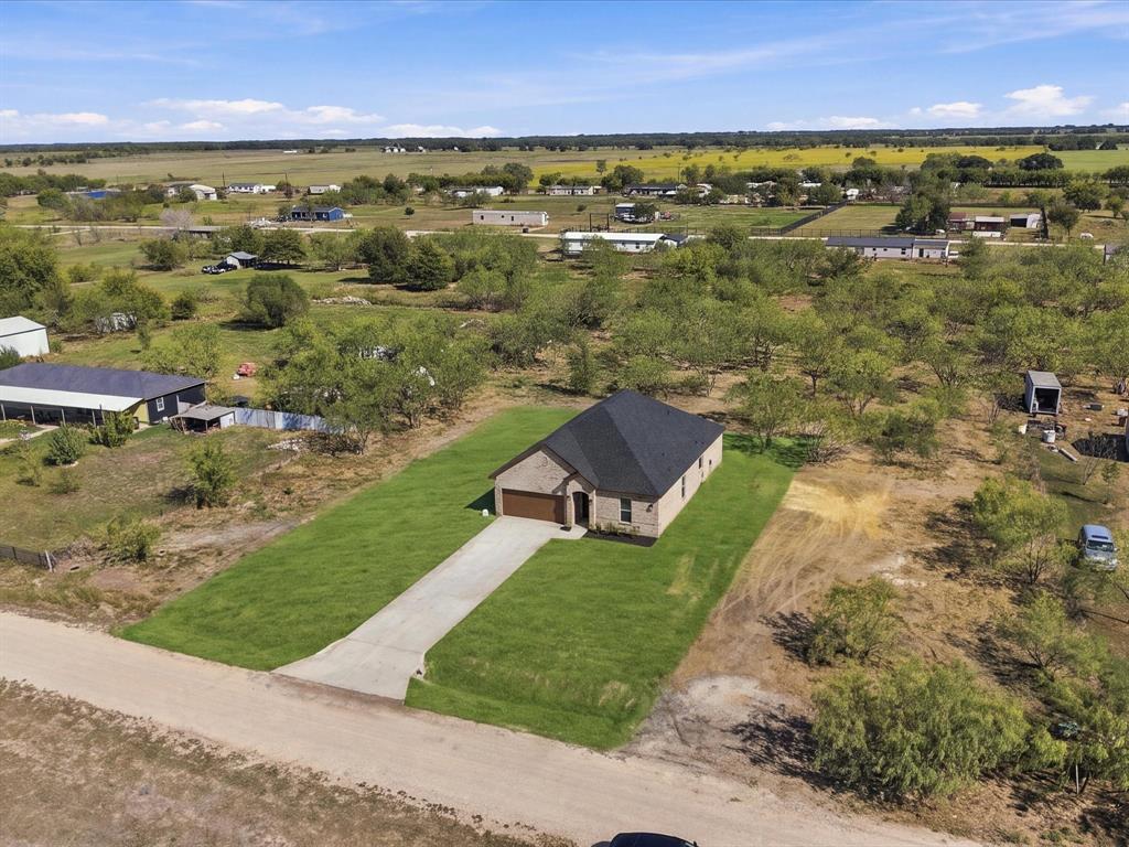 Single-story residence featuring a brick exterior, dark asphalt shingle roof, attached garage, and a concrete driveway situated on a expansive lot