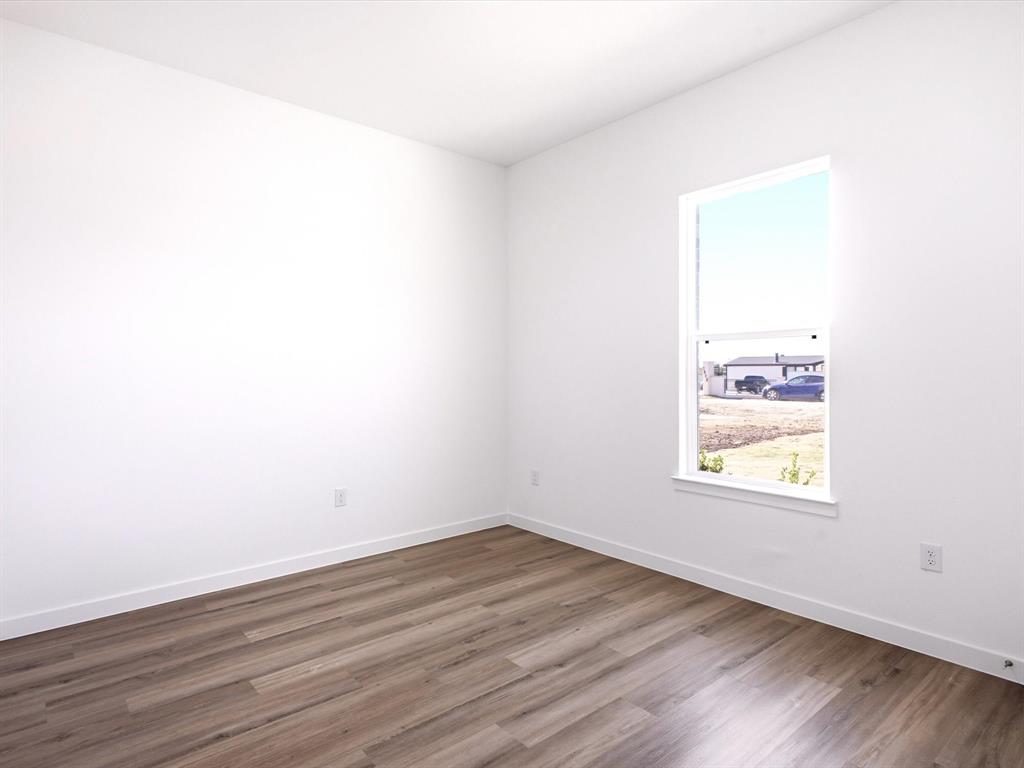 Neutral interior room featuring wood-finish flooring, white walls, and a single-hung window with a sill