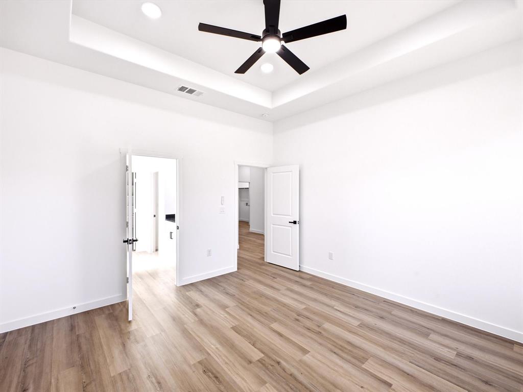 Tray ceiling featuring recessed lighting, matte black ceiling fan, wood-finish flooring, and solid-core doors with matte black hardware