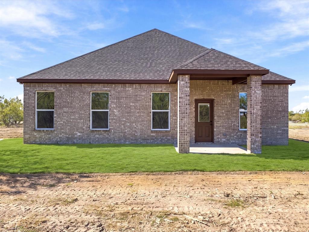 Single-story brick exterior featuring a multi-pitched shingle roof, covered entryway with stone-accented pillars, and vertical-sliding windows