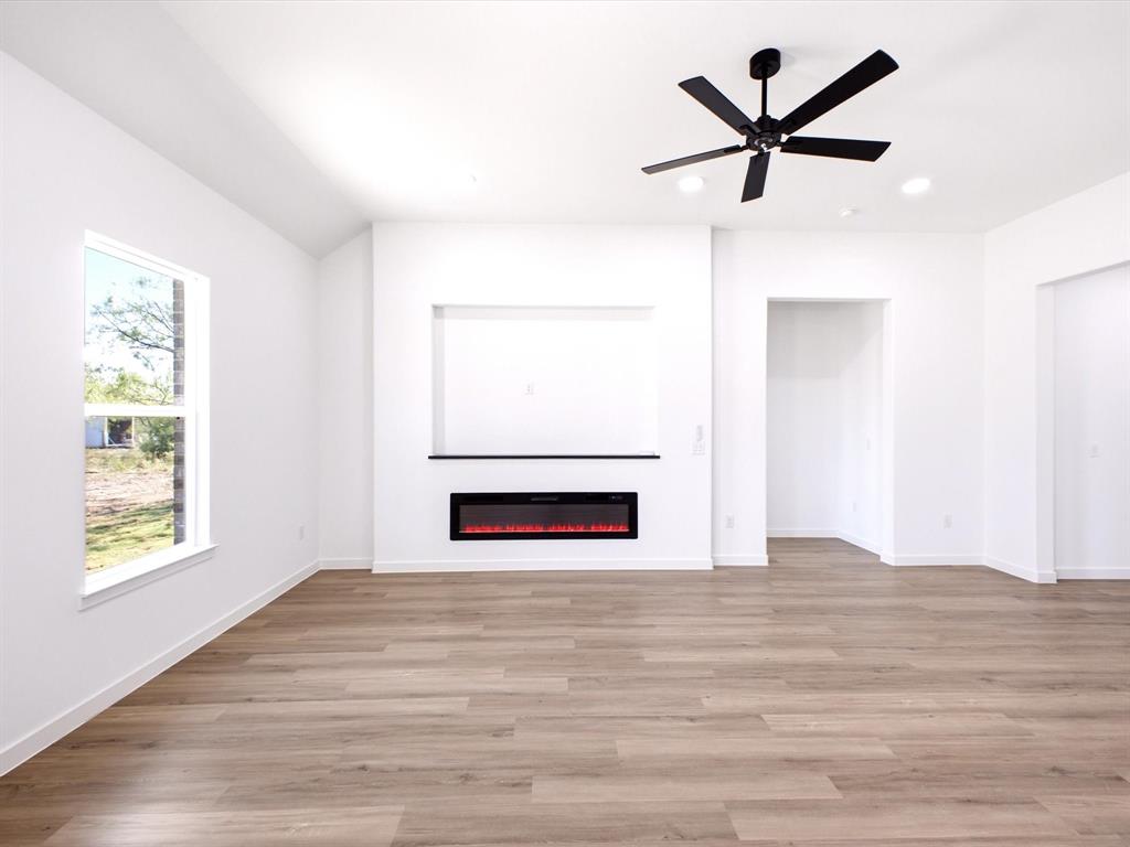 Wood-finish flooring, recessed lighting, matte black ceiling fan, and built-in wall niche with integrated electric fireplace