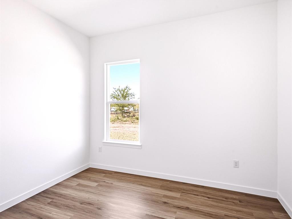 Neutral-toned walls, wood-finish flooring, and a vertical window providing natural illumination