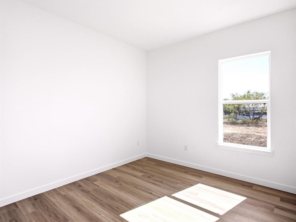 Neutral interior featuring white walls and wood-finish flooring with a single-pane window