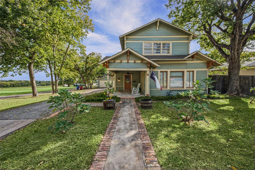 Two-story Craftsman-style exterior featuring horizontal siding, a covered front porch with decorative brackets, and a brick-bordered concrete walkway