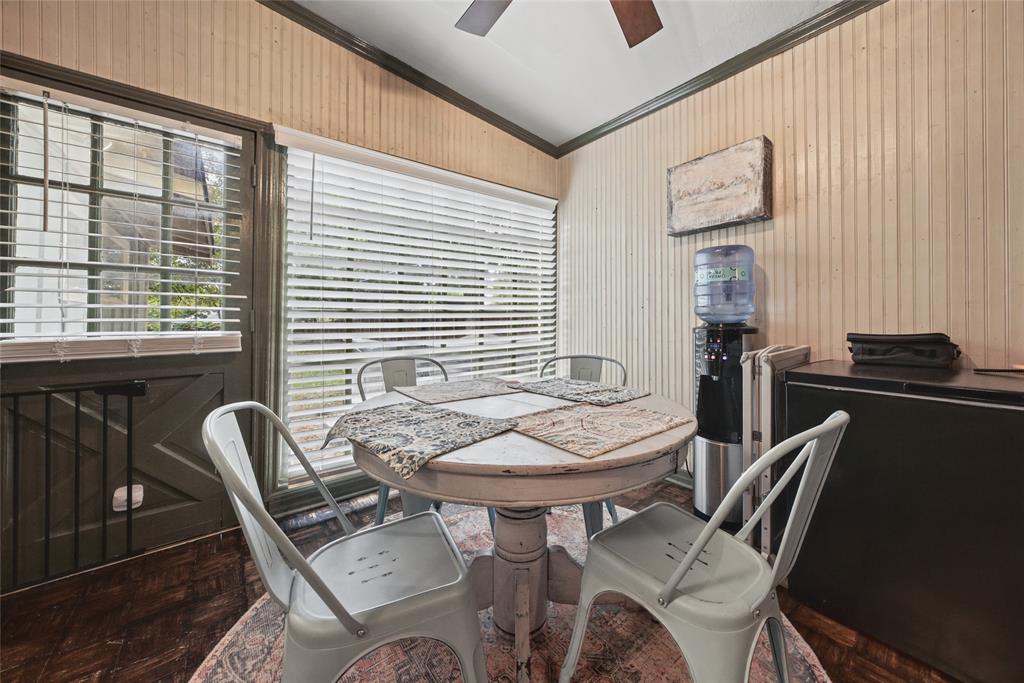 Beadboard wall paneling, expansive multi-pane windows with horizontal blinds, wood-finish flooring, and a ceiling fan with integrated lighting