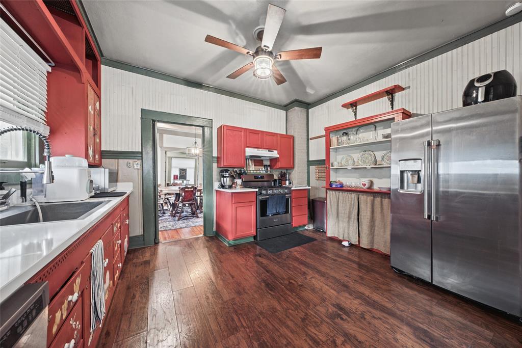 Kitchen featuring wood-finish flooring, beadboard wall paneling, stainless steel refrigerator, built-in display shelving, and ceiling-mounted light fixture