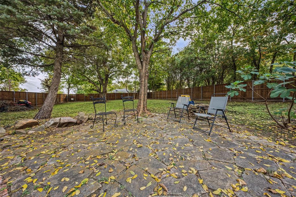 Flagstone patio featuring mature trees, natural rock outcroppings, and perimeter wood fencing