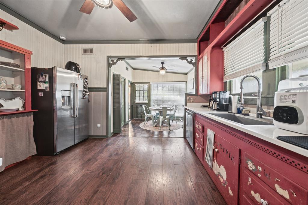 Kitchen featuring wood-finish flooring, stainless steel refrigerator, white countertops, dual-basin sink, and built-in cabinetry