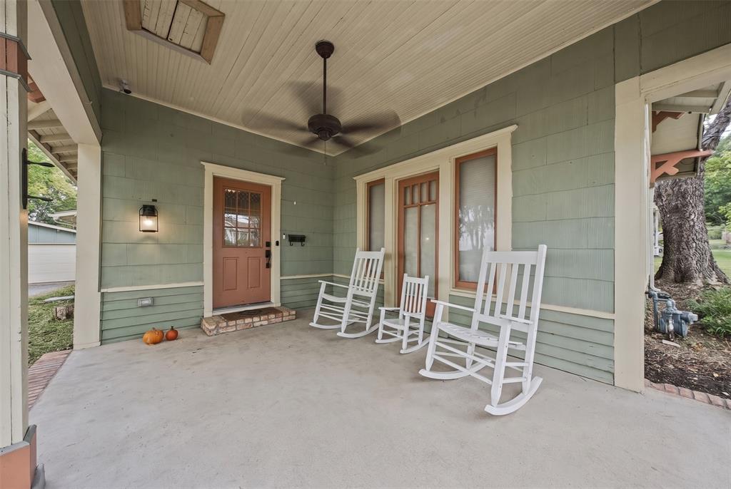 Covered front porch featuring wood-shingle siding, beadboard ceiling, brick-trimmed entryway, and a ceiling fan