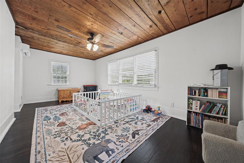 Exposed wood-plank ceiling, dark wood-finish flooring, and multi-pane windows with horizontal blinds