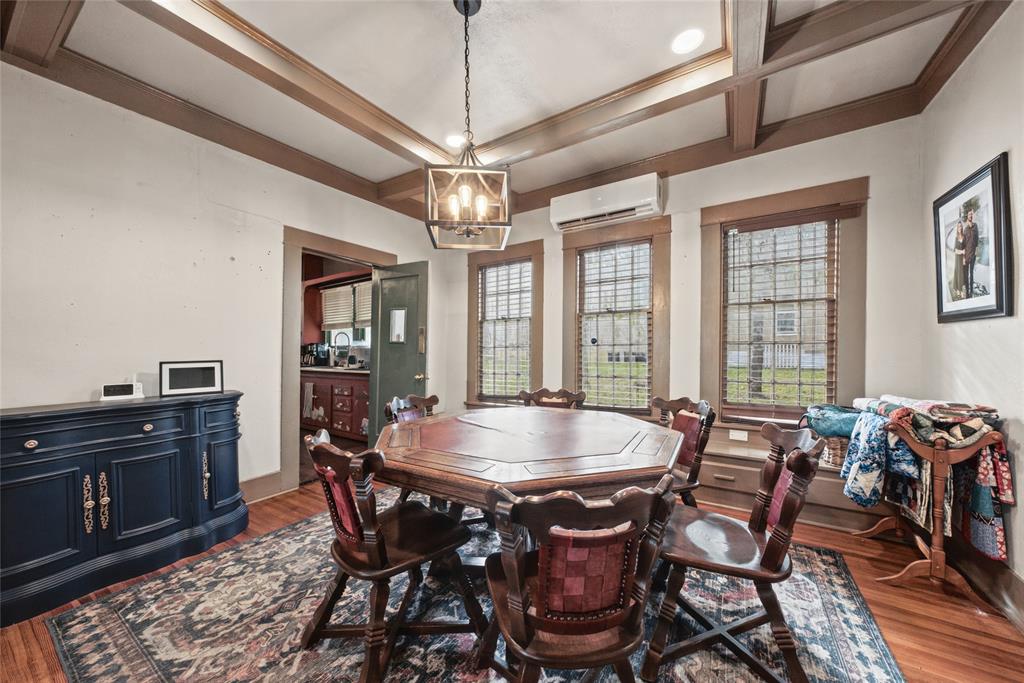 Coffered ceiling with integrated recessed lighting, decorative hanging lantern fixture, multi-pane windows with built-in bench seating, and wood-finish flooring