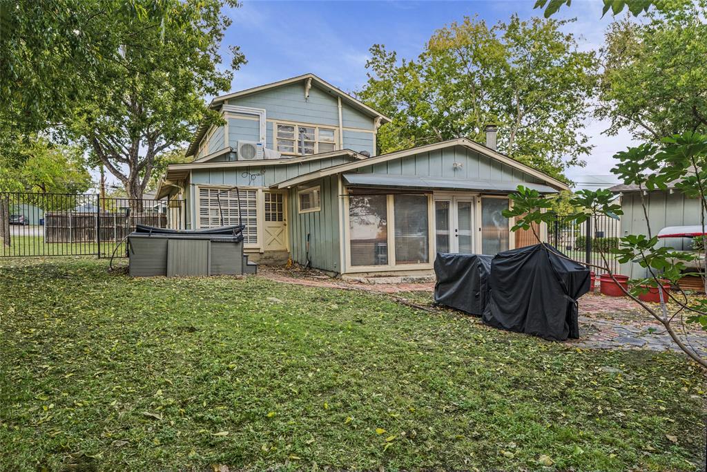 Two-story residence featuring vertical siding, a paved patio area, metal perimeter fencing, and mature trees