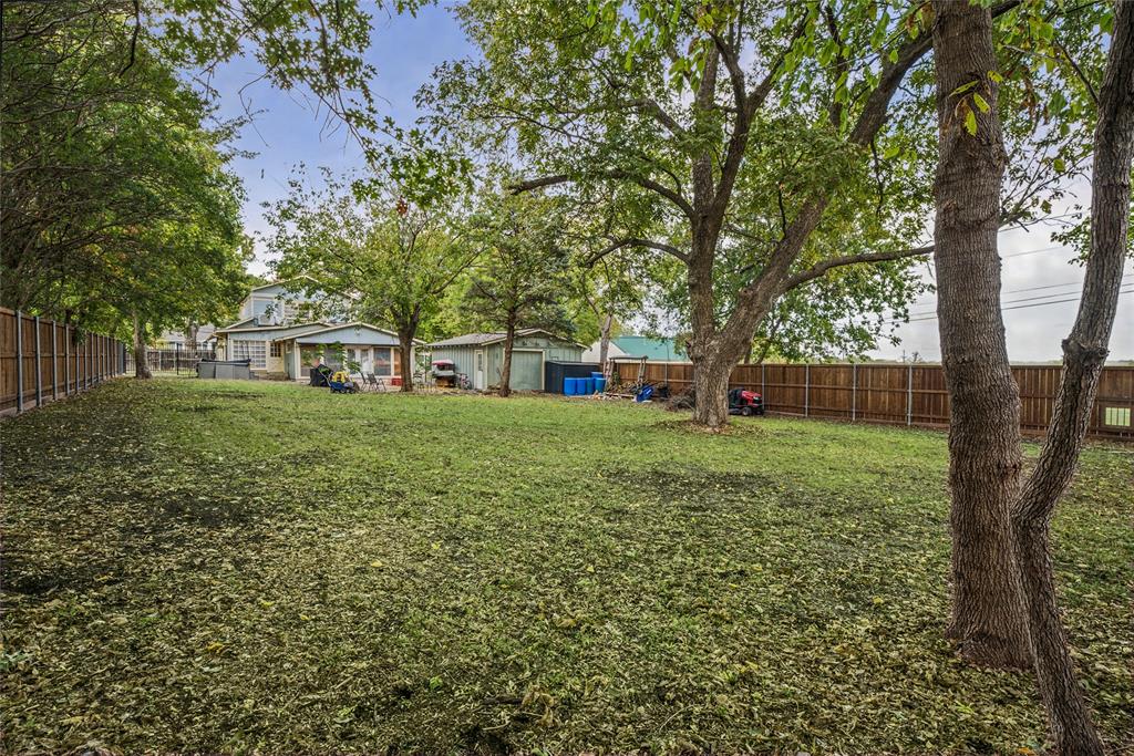 Expansive backyard featuring a fenced perimeter, mature trees, and a detached structure