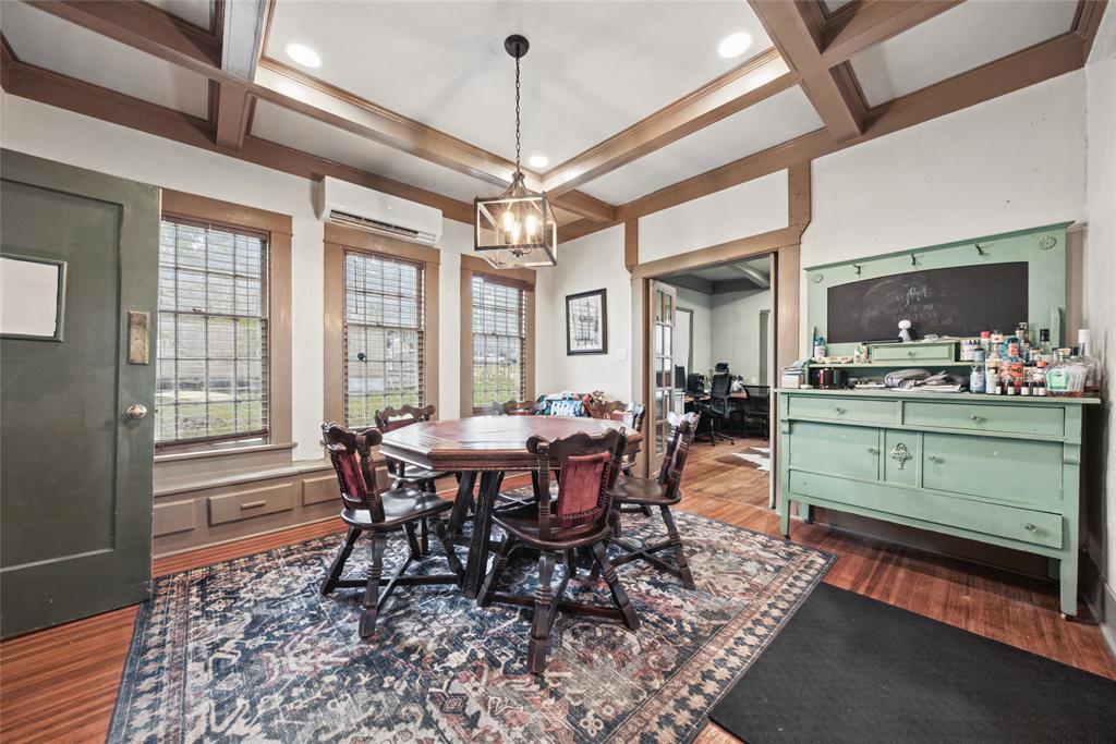 Coffered ceiling with integrated recessed lighting, wood-finish flooring, and multi-pane windows with built-in bench seating