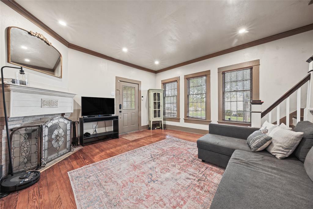 Living area featuring wood-finish flooring, recessed lighting, crown molding, and a fireplace with a decorative mantel and hearth screen