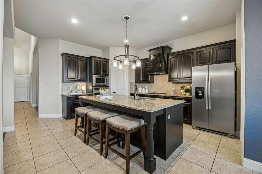 Open kitchen offers granite countertops, stainless steel appliances, abundant cabinetry, island seating and an upgraded kitchen faucet.